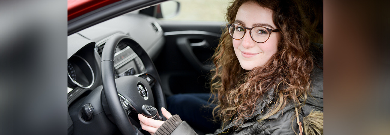 Eine Frau sitzt am Steuer ihres Autos.